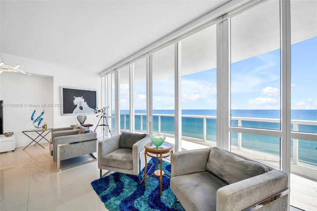 living area with a water view, plenty of natural light, floor to ceiling windows, and tile patterned flooring