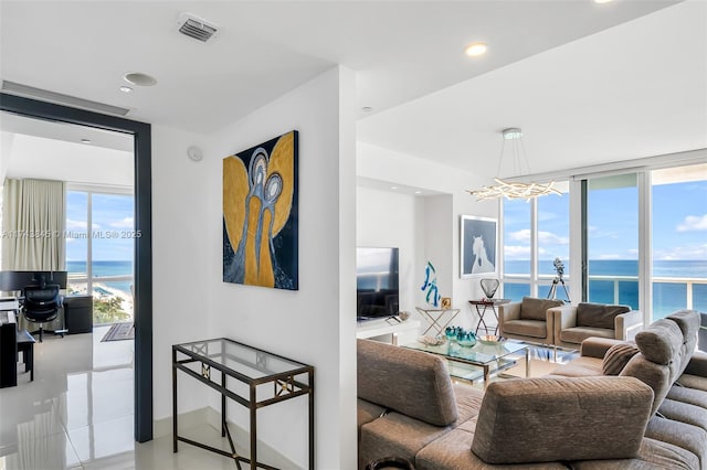 living room featuring recessed lighting, visible vents, a water view, expansive windows, and baseboards