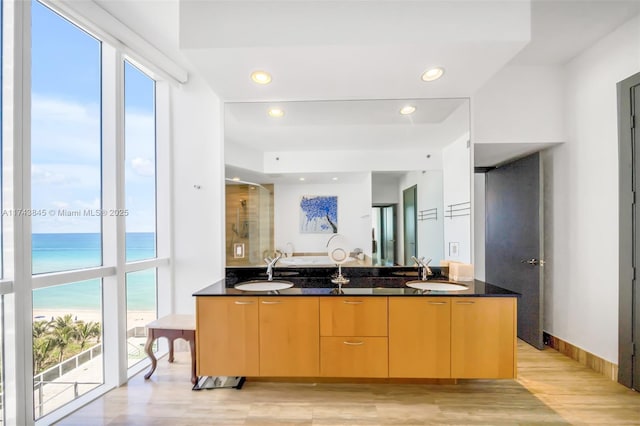 kitchen with light wood-type flooring, a water view, a sink, and modern cabinets