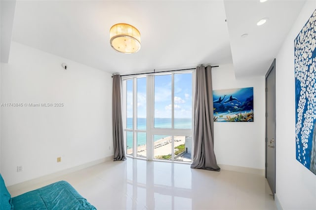 tiled spare room featuring a water view, floor to ceiling windows, baseboards, and recessed lighting