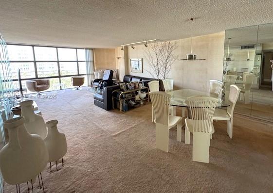 carpeted dining room with a textured ceiling and a wall of windows