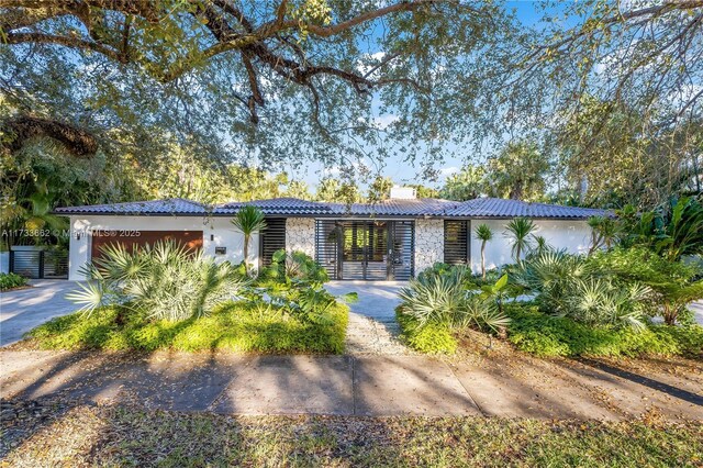 2415 San Domingo St, Coral Gables, FL 33134 - view of front of house featuring driveway, an attached garage, a tile roof, and stucco siding