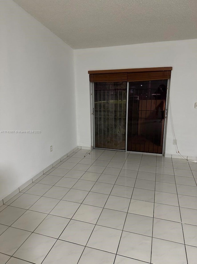 tiled empty room with a textured ceiling