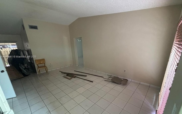 unfurnished living room with lofted ceiling, a textured ceiling, and light tile patterned floors