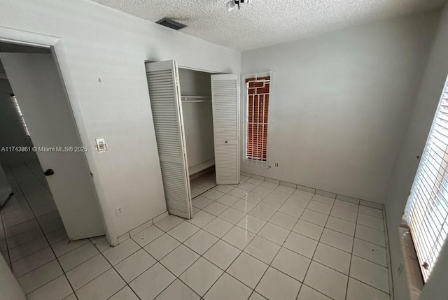 unfurnished bedroom with light tile patterned flooring, a closet, and a textured ceiling