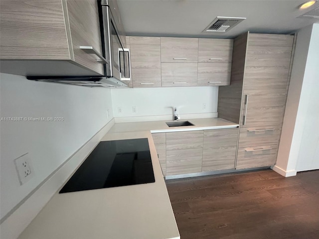 kitchen featuring light brown cabinets, sink, dark wood-type flooring, and black electric cooktop