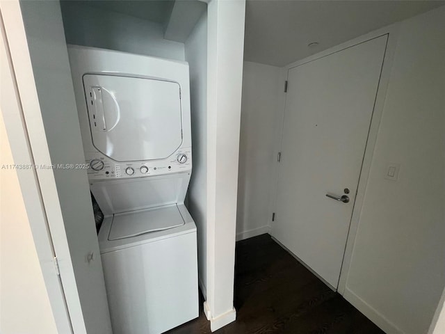 washroom featuring stacked washer / drying machine and dark wood-type flooring