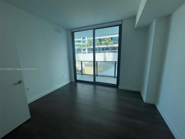 empty room with dark hardwood / wood-style flooring and expansive windows