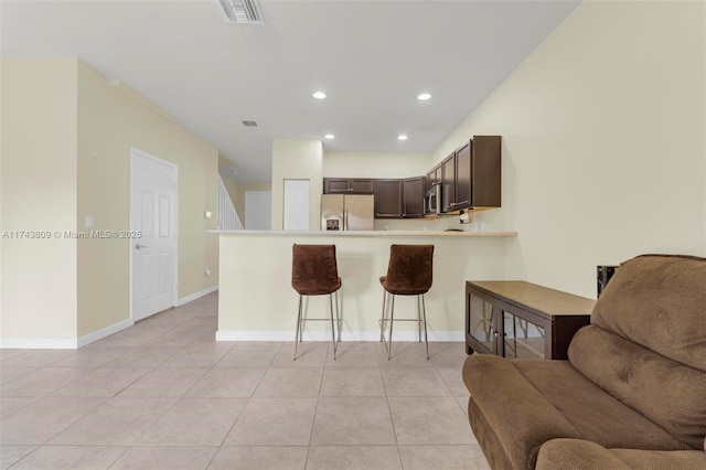 407 SE 32nd Ter, Homestead, FL 33033 - kitchen featuring appliances with stainless steel finishes, a kitchen bar, light tile patterned floors, dark brown cabinetry, and kitchen peninsula