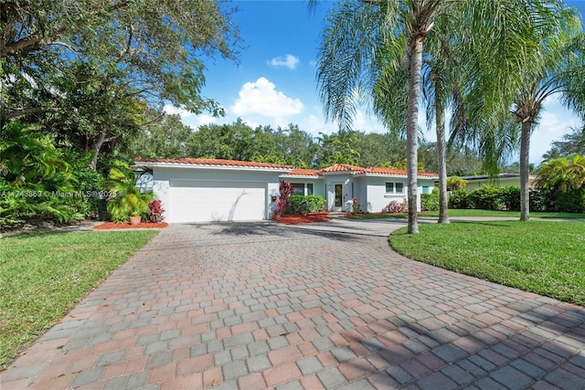 mediterranean / spanish-style home with a garage and a front lawn