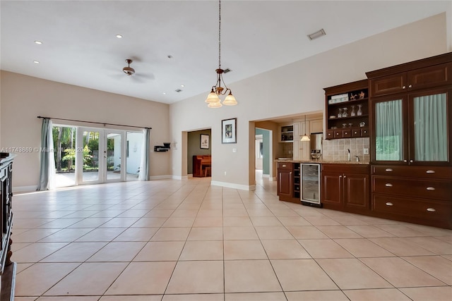 kitchen featuring wine cooler, hanging light fixtures, light tile patterned floors, light stone counters, and dark brown cabinetry