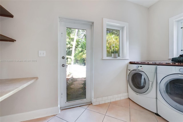 clothes washing area with washing machine and dryer and light tile patterned floors