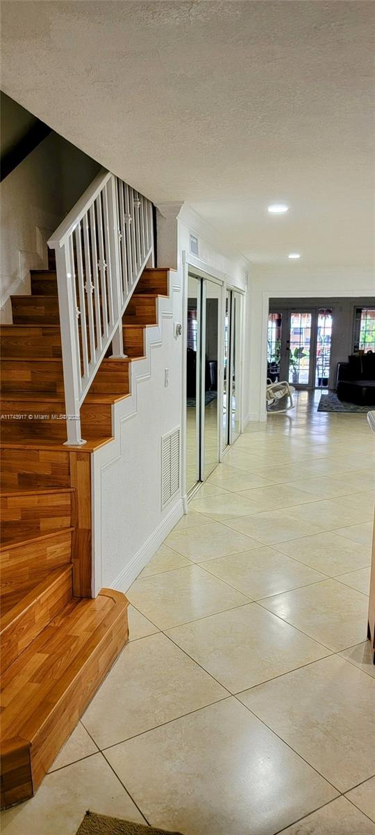 staircase with tile patterned flooring, french doors, and a textured ceiling