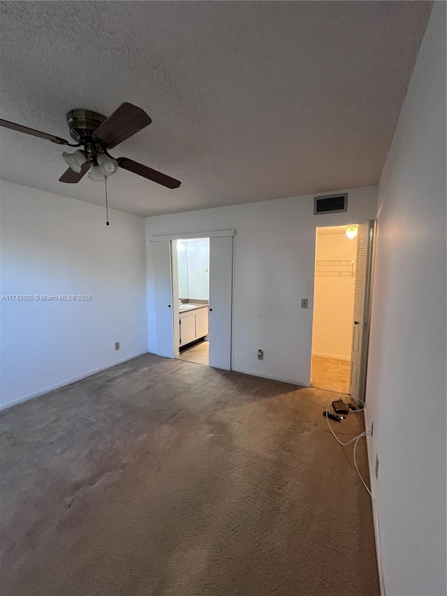 carpeted spare room featuring ceiling fan and a textured ceiling