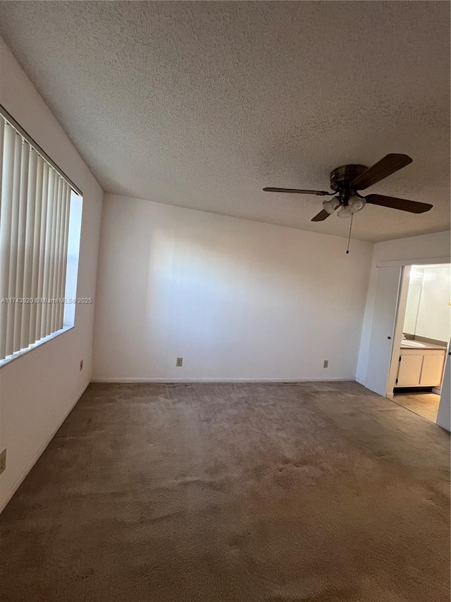 empty room with ceiling fan, light carpet, and a textured ceiling