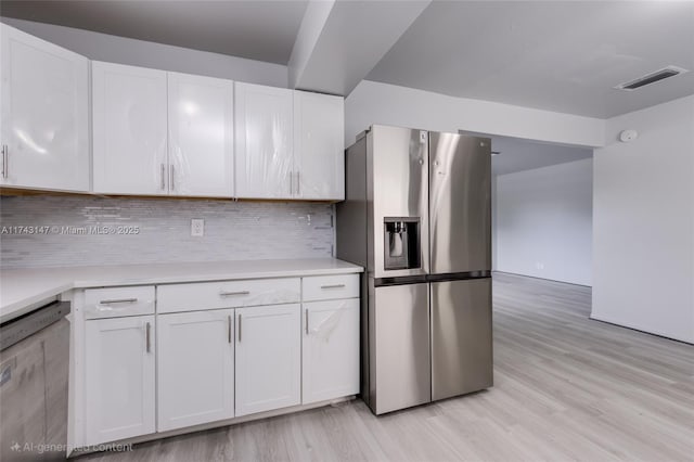 kitchen with appliances with stainless steel finishes, white cabinets, light hardwood / wood-style floors, and decorative backsplash