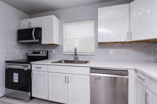 kitchen featuring sink, backsplash, white cabinets, and appliances with stainless steel finishes