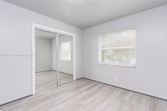 unfurnished bedroom with light hardwood / wood-style floors and a closet