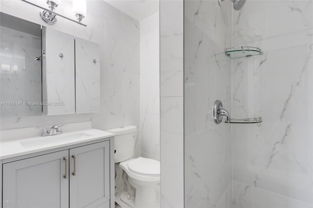 bathroom with vanity, tile walls, toilet, and a tile shower