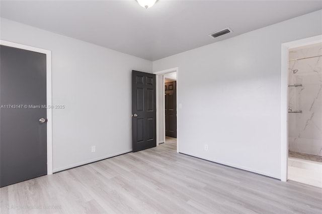 unfurnished bedroom featuring light hardwood / wood-style floors and ensuite bath