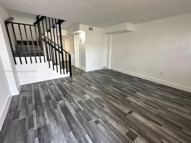 unfurnished living room featuring dark hardwood / wood-style flooring and a textured ceiling