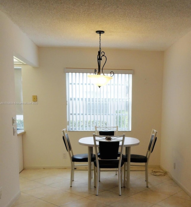 dining area with light tile patterned floors, baseboards, and a textured ceiling