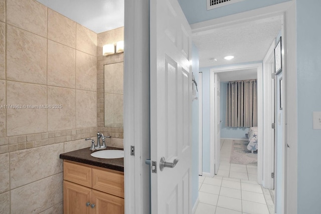 bathroom featuring tile patterned flooring, tile walls, and vanity