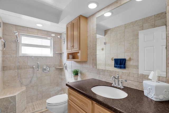 bathroom featuring toilet, tile walls, a shower stall, and vanity