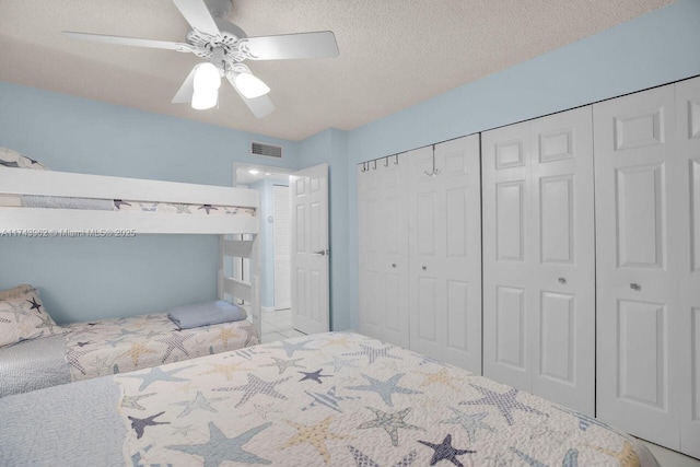 bedroom with a closet, visible vents, ceiling fan, and a textured ceiling