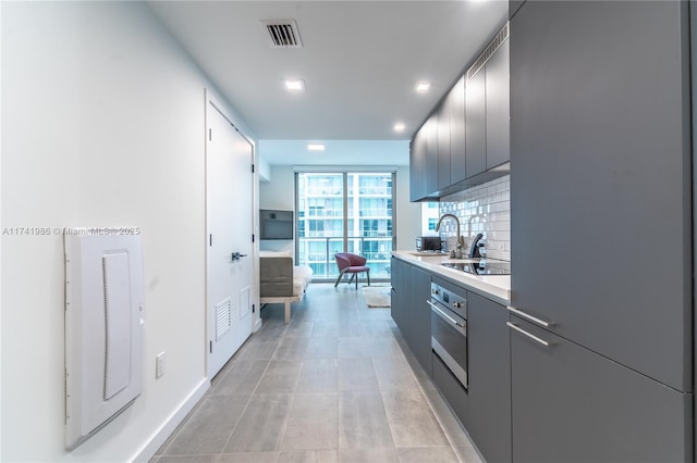 kitchen featuring sink, light tile patterned floors, black electric stovetop, decorative backsplash, and stainless steel oven