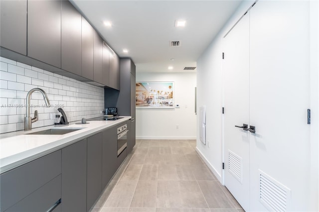 kitchen featuring sink, gray cabinetry, tasteful backsplash, stainless steel oven, and black electric cooktop