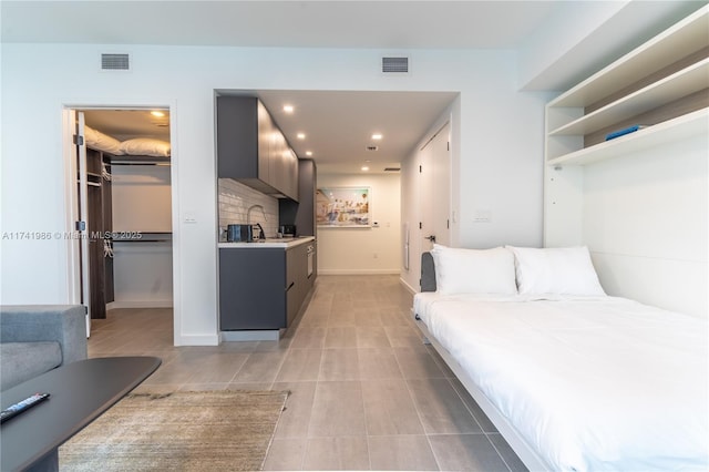 bedroom featuring light tile patterned flooring, a walk in closet, and a closet