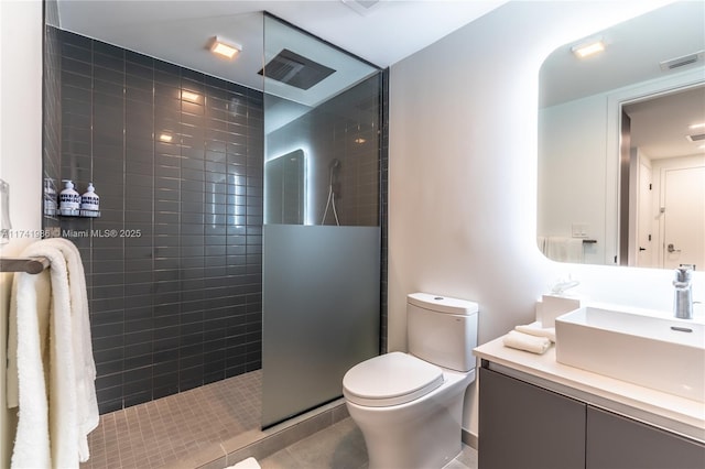 bathroom with vanity, tile patterned flooring, toilet, and tiled shower