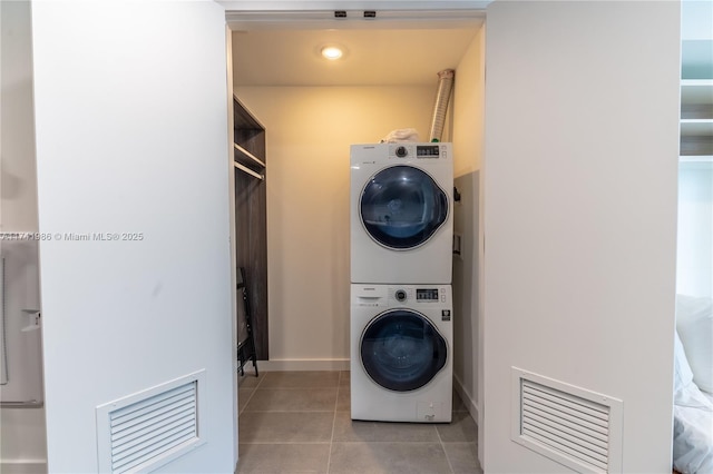 clothes washing area with stacked washing maching and dryer and light tile patterned floors