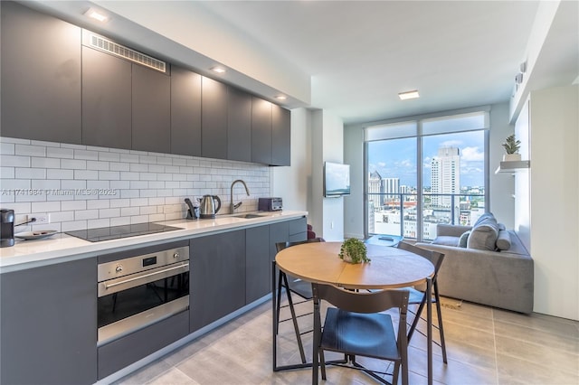 kitchen with tasteful backsplash, stainless steel oven, black electric cooktop, and light tile patterned floors