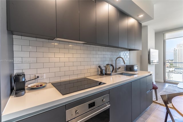 kitchen with floor to ceiling windows, sink, black electric cooktop, oven, and backsplash