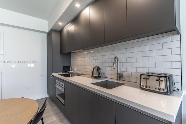 kitchen with sink, tasteful backsplash, black electric stovetop, light tile patterned flooring, and oven