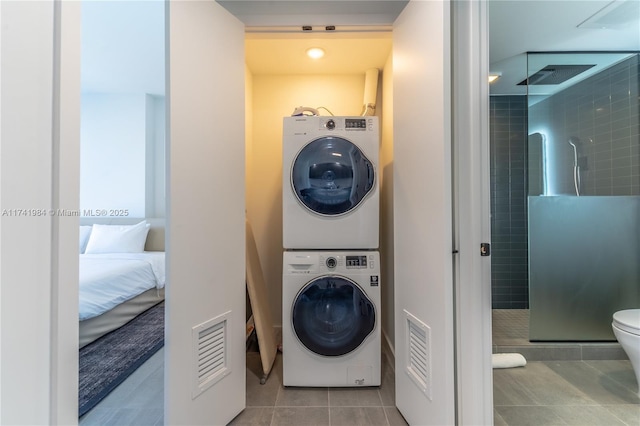 laundry area featuring stacked washer / drying machine and light tile patterned floors