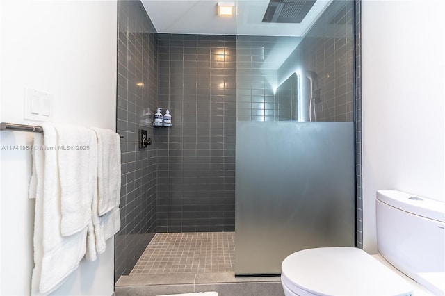 bathroom featuring toilet and tiled shower