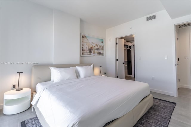 tiled bedroom featuring a walk in closet