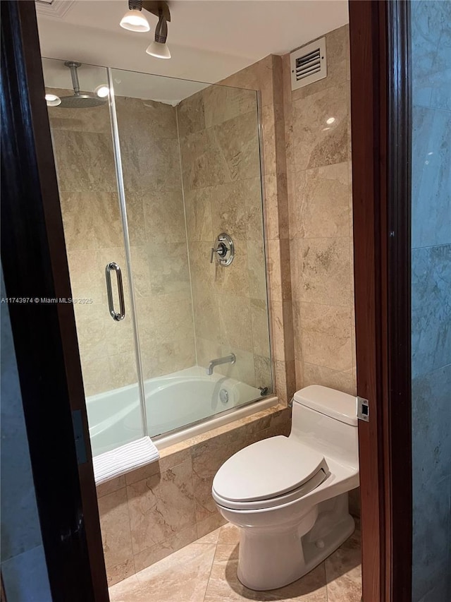 bathroom with tile patterned floors, shower / bath combination with glass door, and toilet