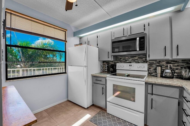 kitchen featuring tasteful backsplash, light tile patterned floors, white appliances, ceiling fan, and a textured ceiling