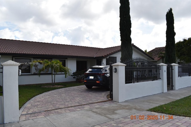 single story home with a fenced front yard, a gate, decorative driveway, and stucco siding