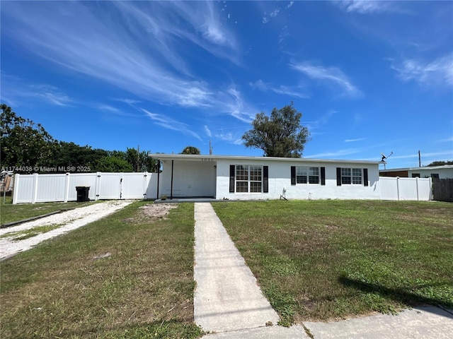 view of front of home featuring driveway, a gate, fence, a front lawn, and stucco siding