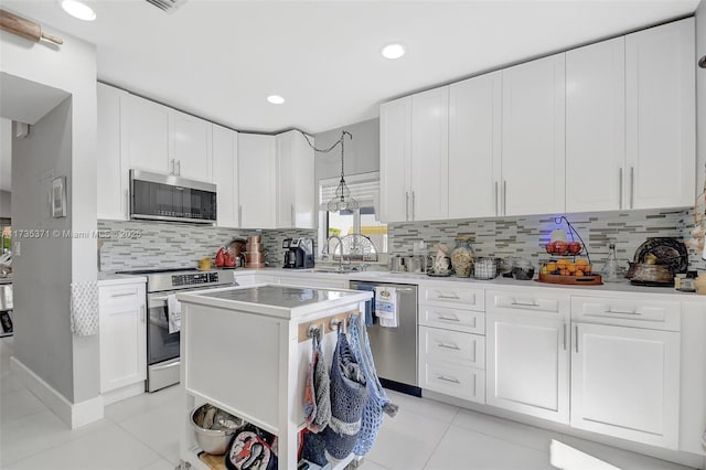 kitchen featuring stainless steel appliances, a center island, white cabinets, and decorative light fixtures