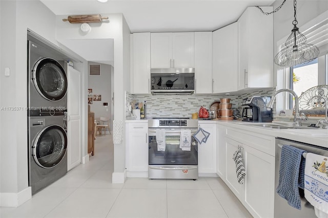 kitchen featuring sink, appliances with stainless steel finishes, stacked washer / dryer, white cabinets, and decorative light fixtures