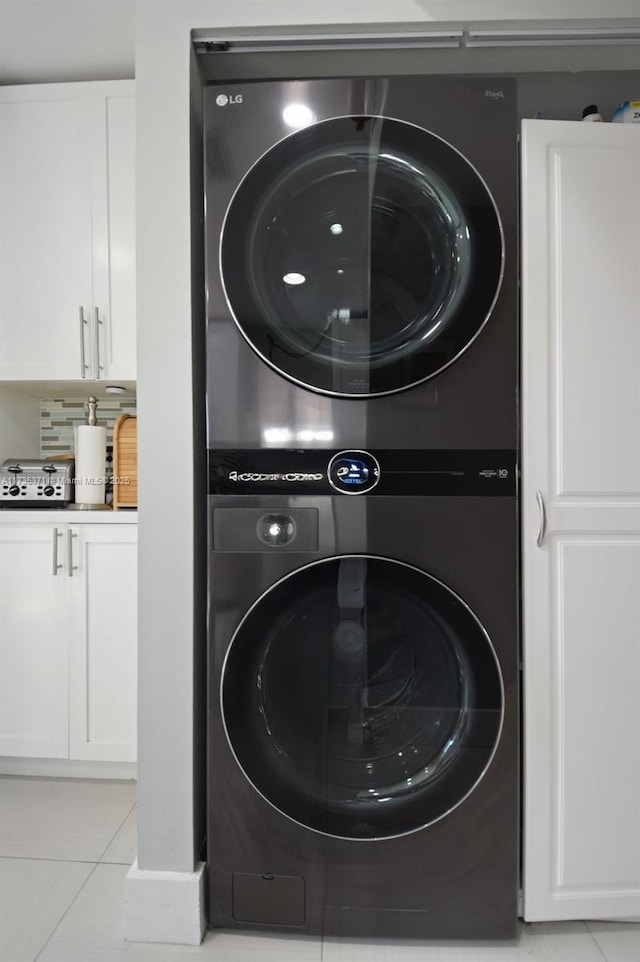 laundry area featuring stacked washer and dryer and light tile patterned floors