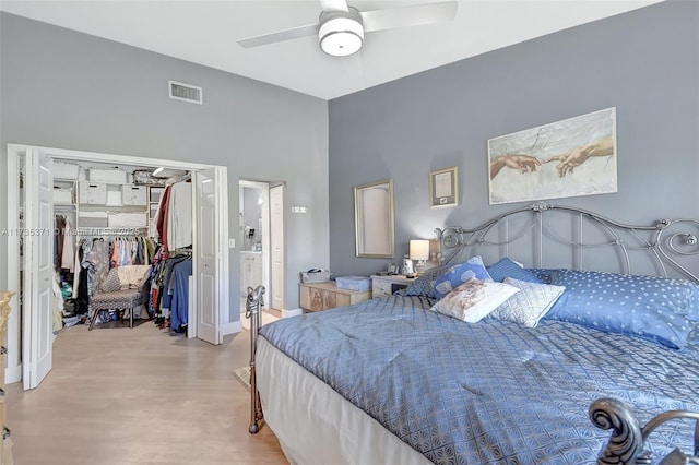 bedroom featuring ceiling fan, ensuite bathroom, a walk in closet, a closet, and light wood-type flooring