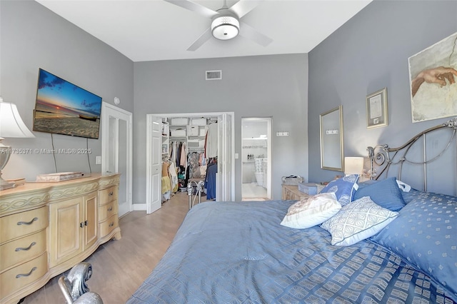 bedroom with ceiling fan, a walk in closet, a closet, and light wood-type flooring