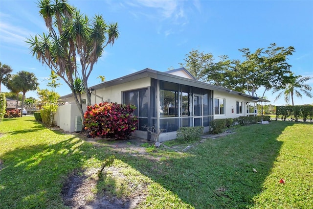 view of side of property with a sunroom and a lawn